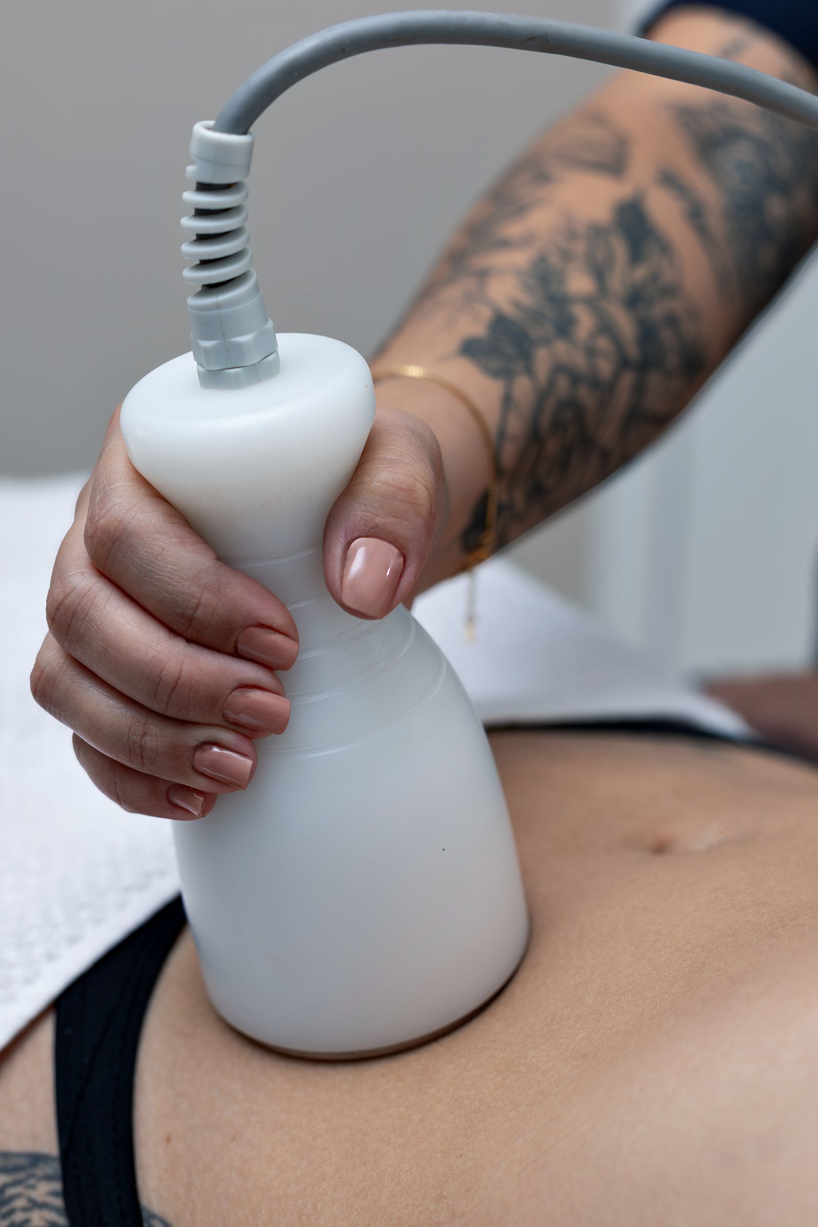 Profesional aplicando un equipo de aparatología sobre el abdomen
